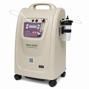 An O2-med portable oxygen concentrator machine in beige with a purple control panel, black wheels, and an attached clear and black gas canister, shown on a white background.